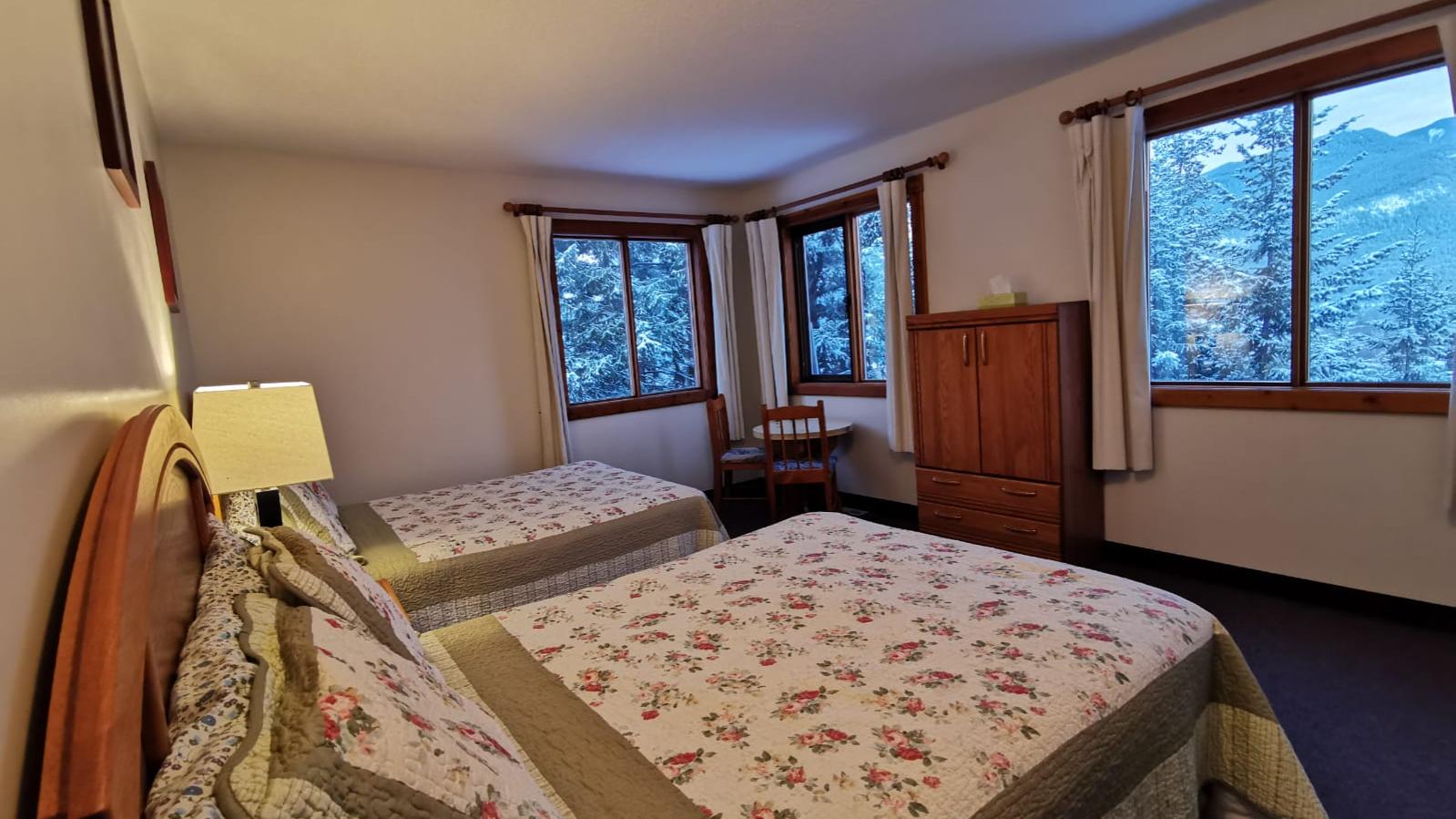 A bedroom with two pine bedsteads covered with cozy quilts.