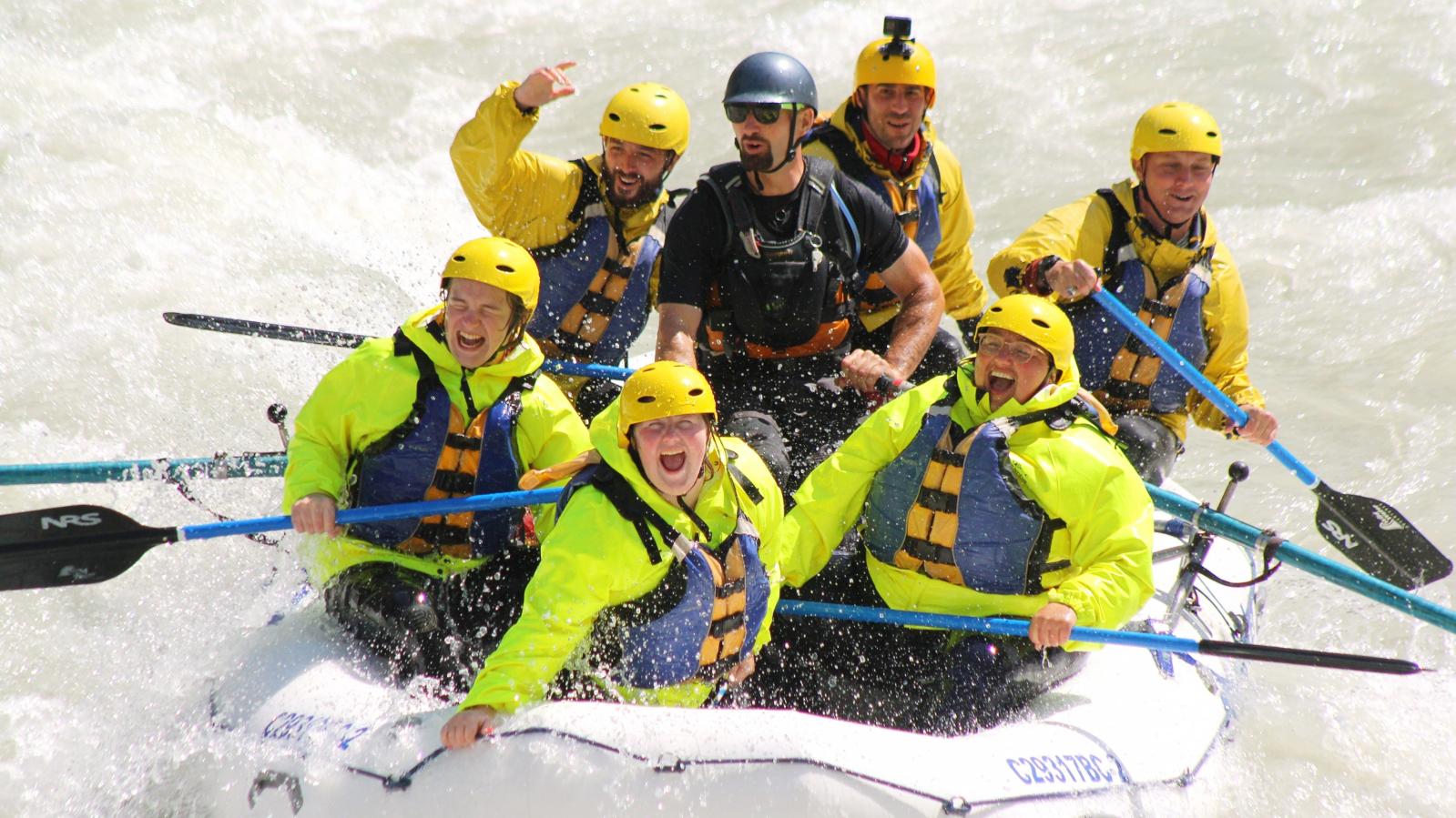 Whitewater rafters in a white raft enjoy the Kicking Horse River whitewater.